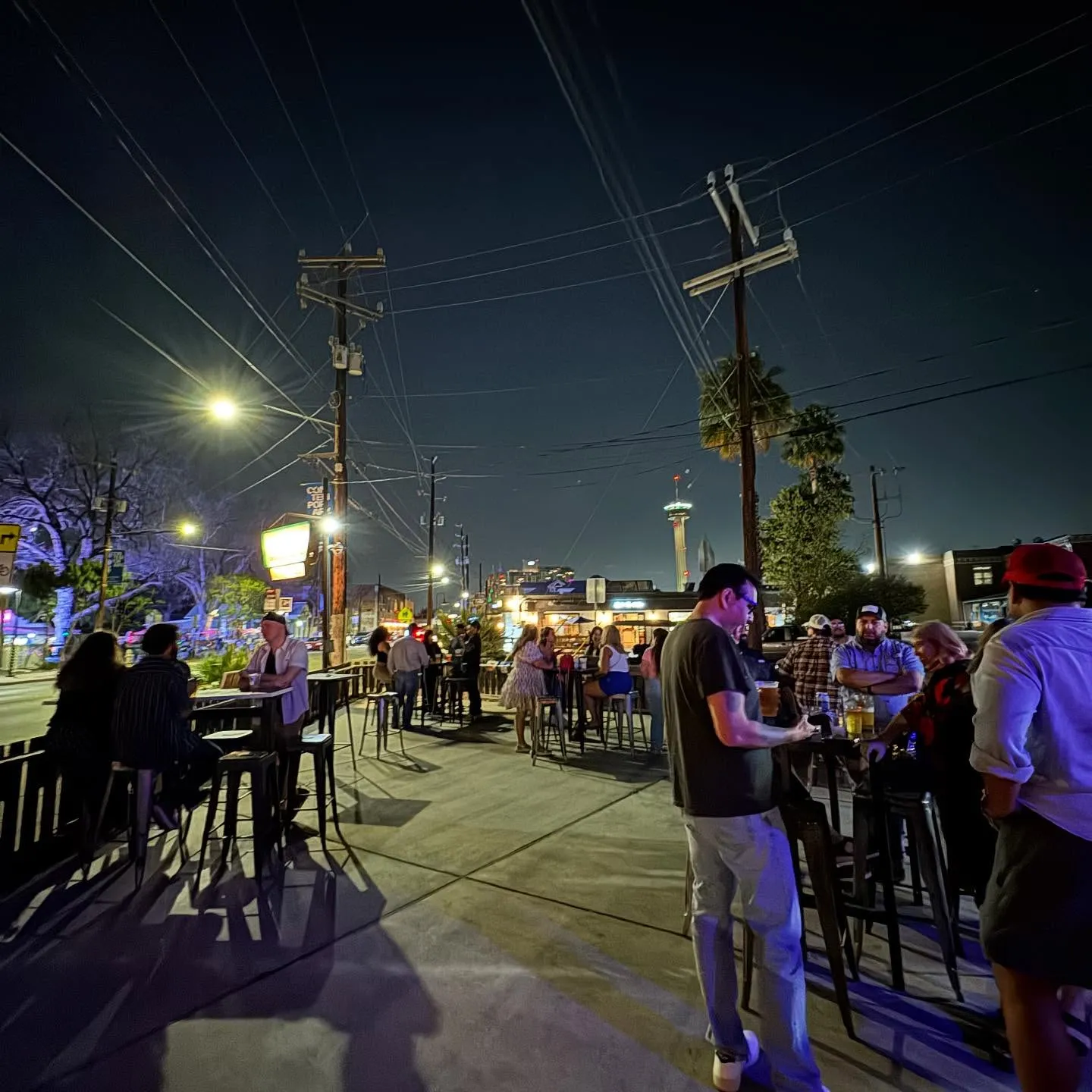 Bruno's packed corner patio at night with Tower of the Americas in the background