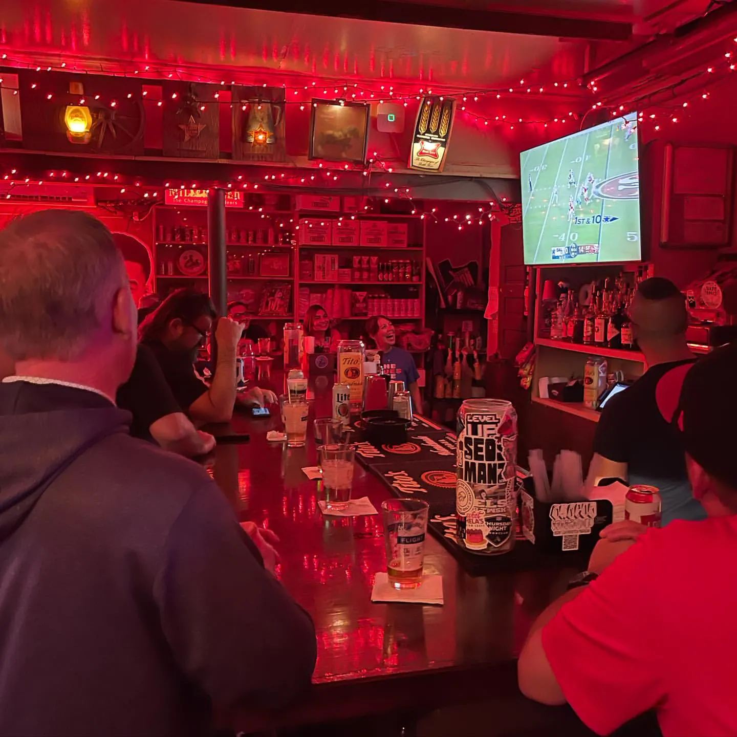 Inside Bruno's Dive Bar — red neon interior with TV and patrons at the bar